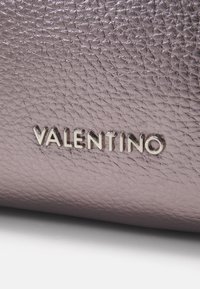 Texturovaná levandulová kůže s kovovým leskem; obsahuje vyražené stříbrné logo značky "VALENTINO".