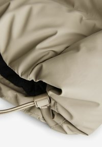 Jachetă izolată bej, cu căptușeală interioară moale, cordon elastic la guler și material exterior neted, rezistent la apă.