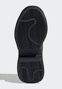Black rubber shoe sole with a wavy tread pattern, featuring a smooth heel and an embossed logo near the heel area.