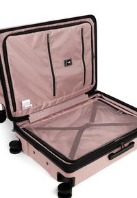 Otevřený růžový tvrdý kufr s síťovanou zipovou přihrádkou, vnitřními zipovými kapsami a čtyřmi schwarzenými kolečky na bílem pozadí.