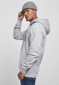 Grå hoodie med en frontlomme, justerbar hætte og ribbede manchetter. Har farverige grafiske bogstaver på brystet og en struktureret strikket hue.