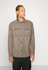 Bruine wollen blend shirtjack met lange mouwen, knoopsluiting aan de voorkant, twee borstzakken en een kraag. Zwarte knopen en een ingetogen ontwerp.