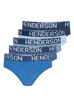 Oberkörperfreier Mann mit kurzen lockigen Haaren, der blaue Slips mit einem dunklen Bund trägt, beschriftet mit "Henderson", steht vor schlichtem Hintergrund.