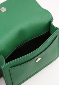 Borsa a tracolla in pelle verde con texture, chiusura a scatto dorata e interno nero. Include una tasca esterna per ulteriore spazio di archiviazione.