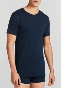 T-shirt in cotone blu navy con maniche corte, scollatura rotonda e vestibilità rilassata, abbinato a pantaloni corti scuri coordinati. Texture morbida e design semplice.