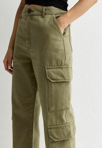 Olijfgroene cargobroek van katoen. Heeft zijzakken, een knoopsluiting en een relaxed fit. Textuurstof met zichtbare stikseldetails.