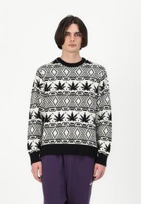 Pleten sweater s crno-bijelim geometrijskim uzorkom s naglascima lišća. Rebrasti manžeti i donji rub, okrugli izrez, slobodan kroj.