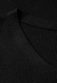 Svart ribbad tröja med detaljer som visar en V-ringad krage och textilstruktur. Har ett mjukt, stretchigt material med ett enhetligt mönster.