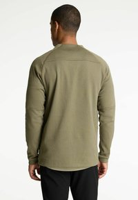 Camisa de manga larga verde oliva con un acabado texturizado, que presenta un dobladillo redondeado y detalles de costura mínimos en la parte posterior.