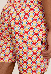 Zwemshorts van lichtgewicht stof, met een geometrisch patroon in rood, blauw, geel en wit. Inclusief een achterzak met een knoop.