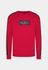 Felpa rossa in misto cotone con una toppa logo nera sul petto. Presenta strisce laterali nere con un motivo logo ripetuto.