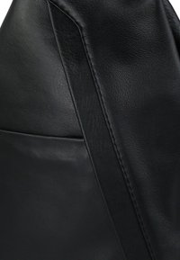 Schwarze Ledertasche mit glatter Textur, gekrümmter Form und breitem Riemen. Enthält eine Einschubtasche an der Seite.