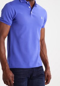 Korte mouwen polo shirt in koningsblauw katoen met een twee-knopen knoopsluiting en een klein geborduurd logo op de borst, gecombineerd met donkere spijkerbroek.