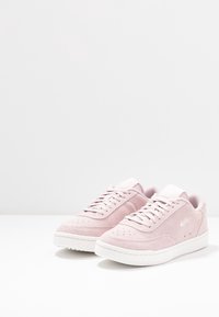 Sneaker basse in suede rosa con superficie testurizzata, suola in gomma bianca e lacci tonali. Presentano un logo bianco sul lato.