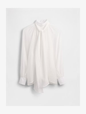 Weiße Bluse mit hohem Kragen, vorne fließend, lange Ärmel und geknöpfte Manschetten. Hergestellt aus einem leichten, transparenten Stoff.