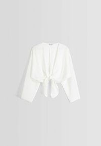 Top avvolgente corto, leggero e bianco con maniche lunghe e chiusura a fiocco sul davanti, caratterizzato da una texture morbida e un design aperto.