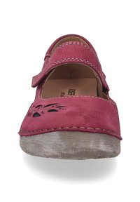 Różowe skórzane buty na pasku, z przeszyciami i wycięciami w kształcie kwiatów. Okrągły czubek i jasnobrązowa gumowa podeszwa dopełniają projekt.