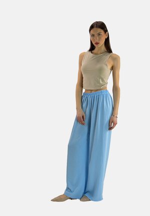 Beige mouwloos shirt en losse, lichtblauwe wijde broek met een elastische tailleband. Glad textuur, minimalistisch ontwerp en relaxte pasvorm.