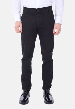 Pantaloni di cotone neri con design a gamba dritta, dotati di chiusura a bottone e tasche laterali, abbinati a lucide scarpe eleganti nere.