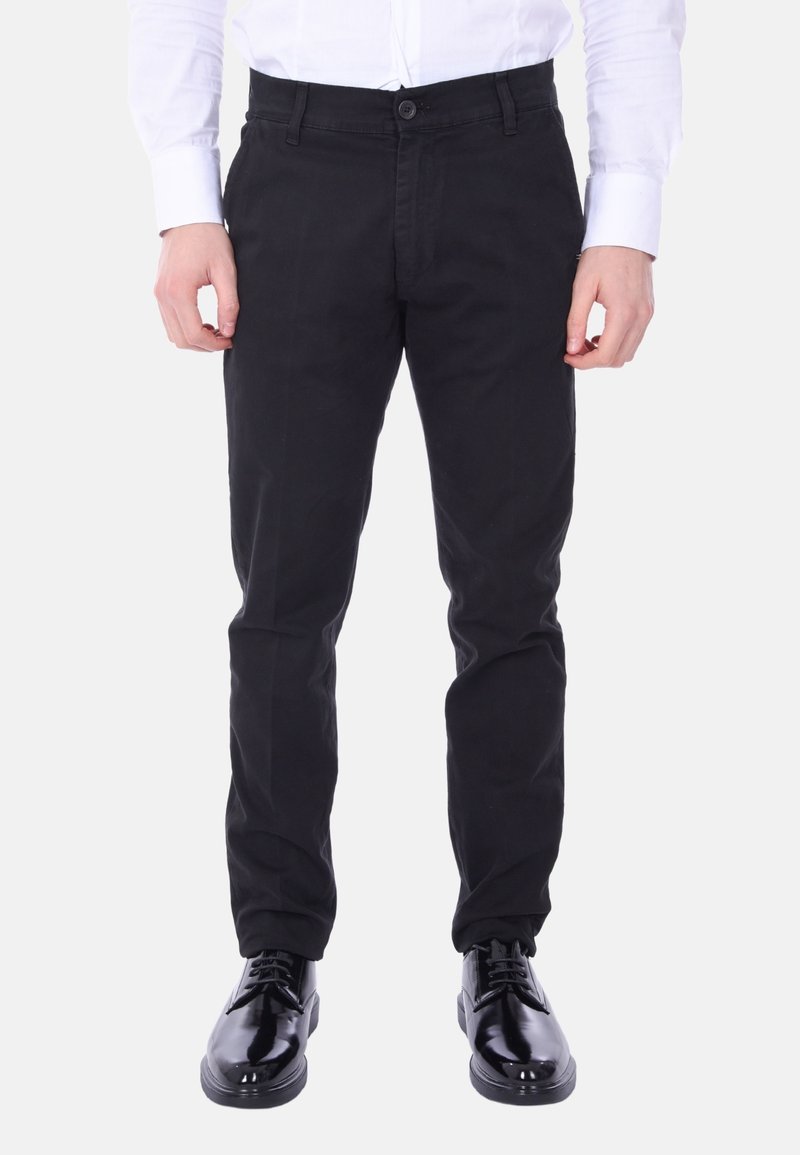 Pantaloni di cotone neri con design a gamba dritta, dotati di chiusura a bottone e tasche laterali, abbinati a lucide scarpe eleganti nere.