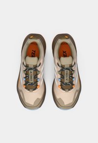 Μπεζ και καφέ αθλητικά παπούτσια με υφή, διακοσμητικά μοτίβα και μπλε λεπτομέρειες στα κορδόνια και στην σόλα. Διακριτό λογότυπο της μάρκας.
