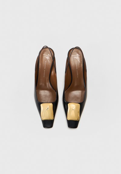 Black leather slingback shoes with a square toe, featuring a large gold accent on the front and a smooth brown insole.