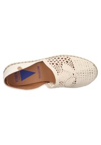 Zapato de lona beige tipo slip-on con un diseño de ganchillo abierto, punta redonda y una suela plana estilo espadrille trenzada. Presenta un logo en azul.