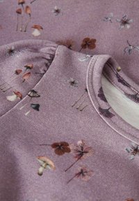 Zacht paarse stof met kleine paddenstoelen- en bloemenprints, die een close-up toont van een ronde halslijn en de geplooide mouwdetails.