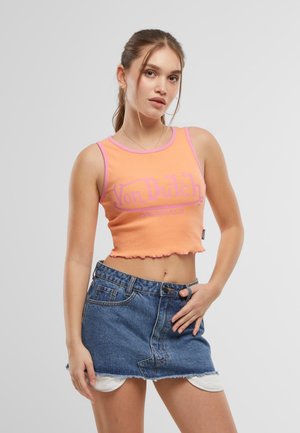 Lys oransje crop topp med rosa kant og "Von Dutch"-logo, kombinert med et denim mini skjørt med frynsete kant og frontlommer.