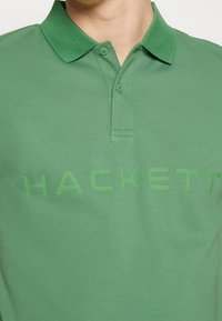 Polo vert en mélange de coton. Doté d'un col, de manches courtes et d'un logo "HACKETT" en relief de teinte assortie.