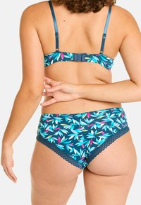 Soutien-gorge à motif floral et culotte assortie en bleu canard foncé avec des feuilles roses et bleues. Dentelle sur le bord de la culotte. Bretelles ajustables sur le soutien-gorge.