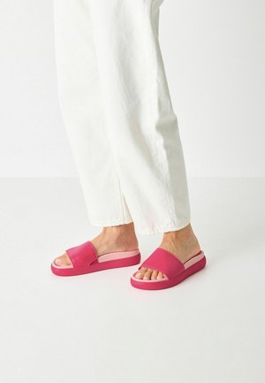 Rosa halksandaler med en bred rem och en dämpad sula. Designen har en tjock, solid bas och en öppen tå.