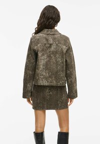 Veste en simili cuir marron avec un design en imprimé serpent, dotée d'un col classique et de manches longues, associée à une jupe assortie.