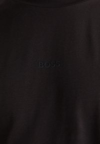 Črna bombažna majica s kratkimi rokavi in okroglim izrezom, ki se ponaša z diskretno embosirano oznako "BOSS" na prsih, gladko teksturo in standardnim krojem.
