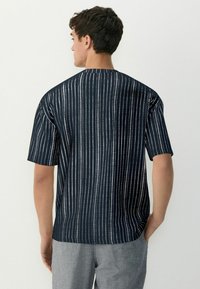 Short-sleeve shirt in navy with white vertical stripes. Lightweight fabric, relaxed fit, crew neckline, and straight hem design.