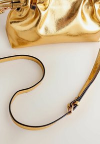 Kultainen metallinen clutch-laukku, jossa on ryppyinen muotoilu, irrotettavalla olkahihnalla mustilla reunoilla ja kullansävyyllä. Jännittävä pinta, kiiltävä viimeistely.