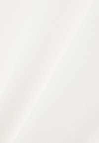 Deux échantillons de tissu blanc superposés avec des textures et motifs subtils visibles sous un éclairage doux.