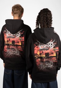 Svart hettegenser med et fargerikt grafisk design av Londons skyline, med bygninger, abstrakte mønstre og UFO-motiver på baksiden.