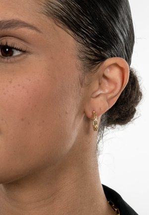 Gold hoop earrings with a linked chain design, featuring a smooth surface and shiny finish, worn on a model's ear.