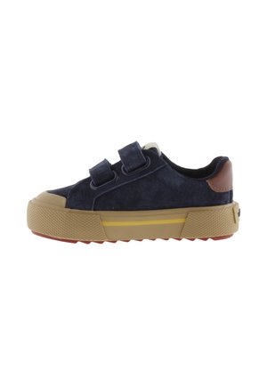 Baskets enfant bleu marine avec deux bandes velcro, semelle en caoutchouc beige avec bande jaune et pièce en cuir marron au talon.