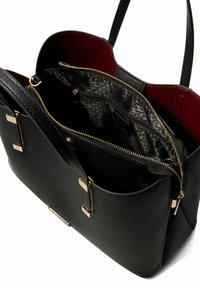 Black leather handbag featuring gold hardware, a textured exterior, and a red interior. Includes a zippered pocket and two compartments.