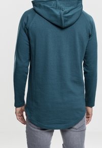 Felpa con cappuccio color verde acqua con orlo arrotondato, maniche lunghe e tasca a marsupio frontale. Tessuto morbido con texture liscia, con cappuccio regolabile tramite coulisse.