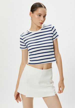 Stribet crop top i hvid og navy, korte ærmer, ribbet tekstur. Sammen med en højtaljet hvid mini skirt.