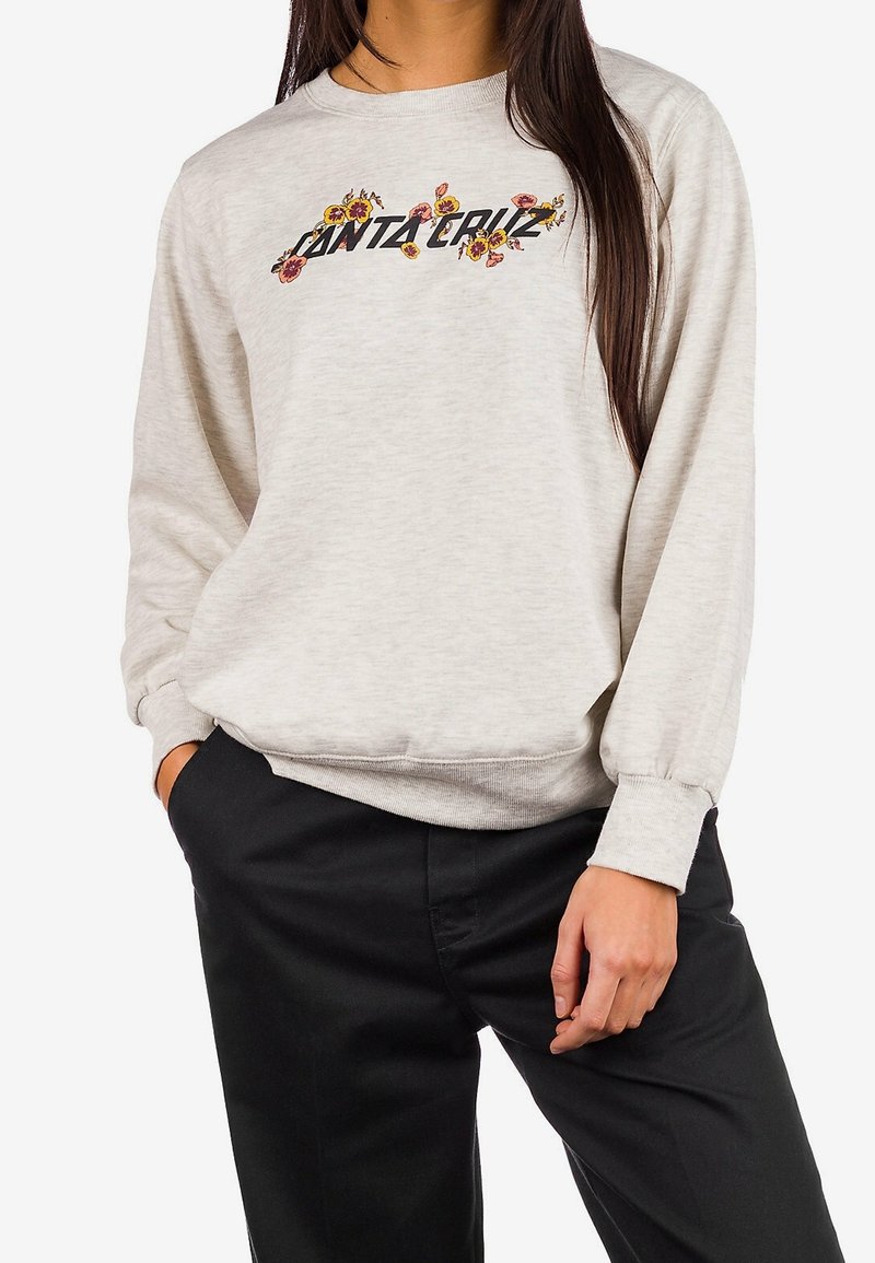 Felpa grigia con ricami floreali che presenta il testo "Santa Cruz." Polsini e orlo a costine; tessuto morbido e testurizzato. Abbinata a pantaloni neri.