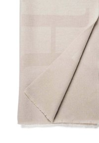 Tissu doux beige clair avec un motif subtil ; un bord replié, révélant une surface lisse et un ourlet effiloché. Conçu pour la chaleur et le confort.