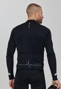 Schwarzes langärmliges Radtrikot mit passgenauem Design, glatter Textur, reflektierenden Details an den Ärmeln und einem Herzschlaglinien-Graphic auf dem Rücken.