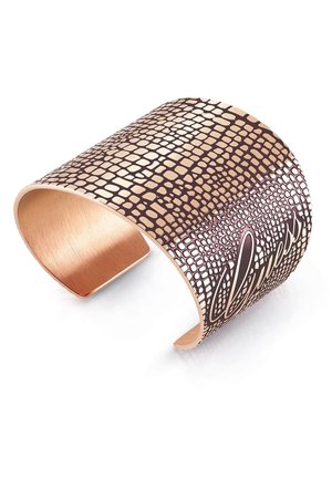 Brazalete ancho de oro rosa con un patrón texturizado similar a un reptil y la palabra "bendecido" grabada en cursiva.