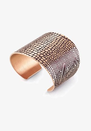 Large bracelet manchette en or rose avec un motif texturé rappelant la peau de reptile et le mot « béni » gravé en cursive.