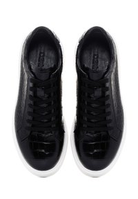 Un par de zapatillas de cuero negro con textura de cocodrilo, con cordones negros y suelas blancas, vistas desde arriba.