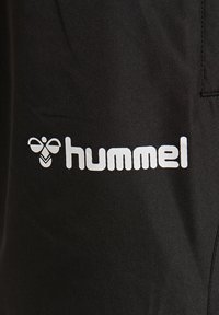 Svart klädsel med en vit "hummel"-logotyp och bik grafik; slät textur; enkel och modern design; inga ytterligare mönster.